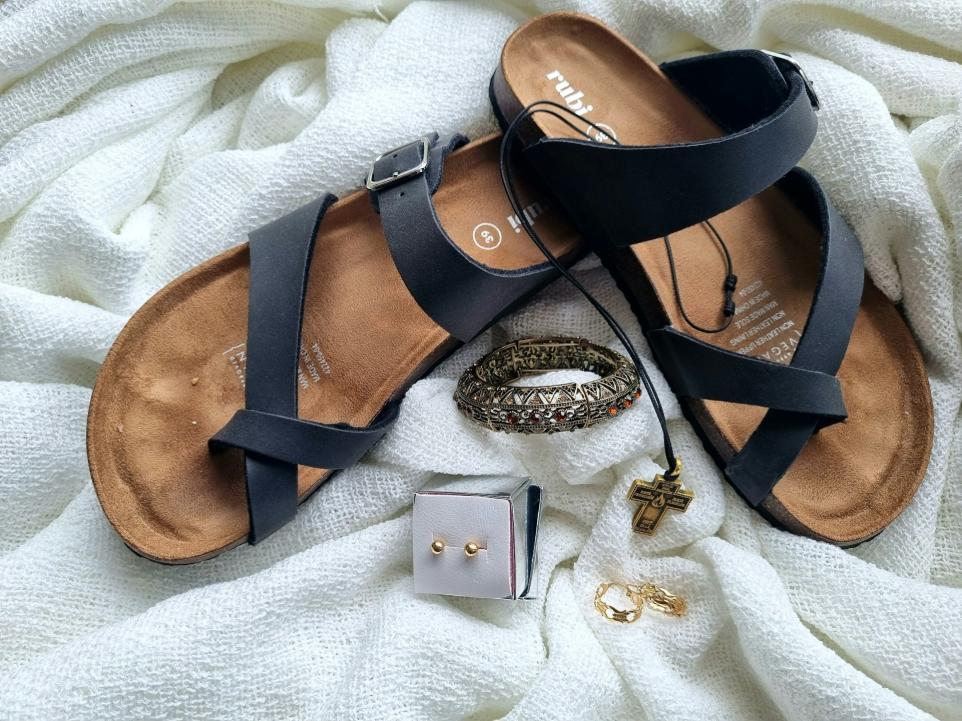 a pair of sandals, a ring, and a bracelet on a white blanket